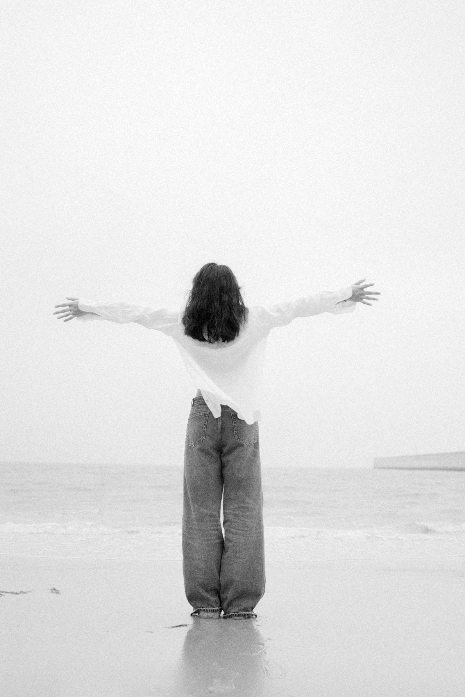 A woman standing with arms stretched in wide-leg trousers