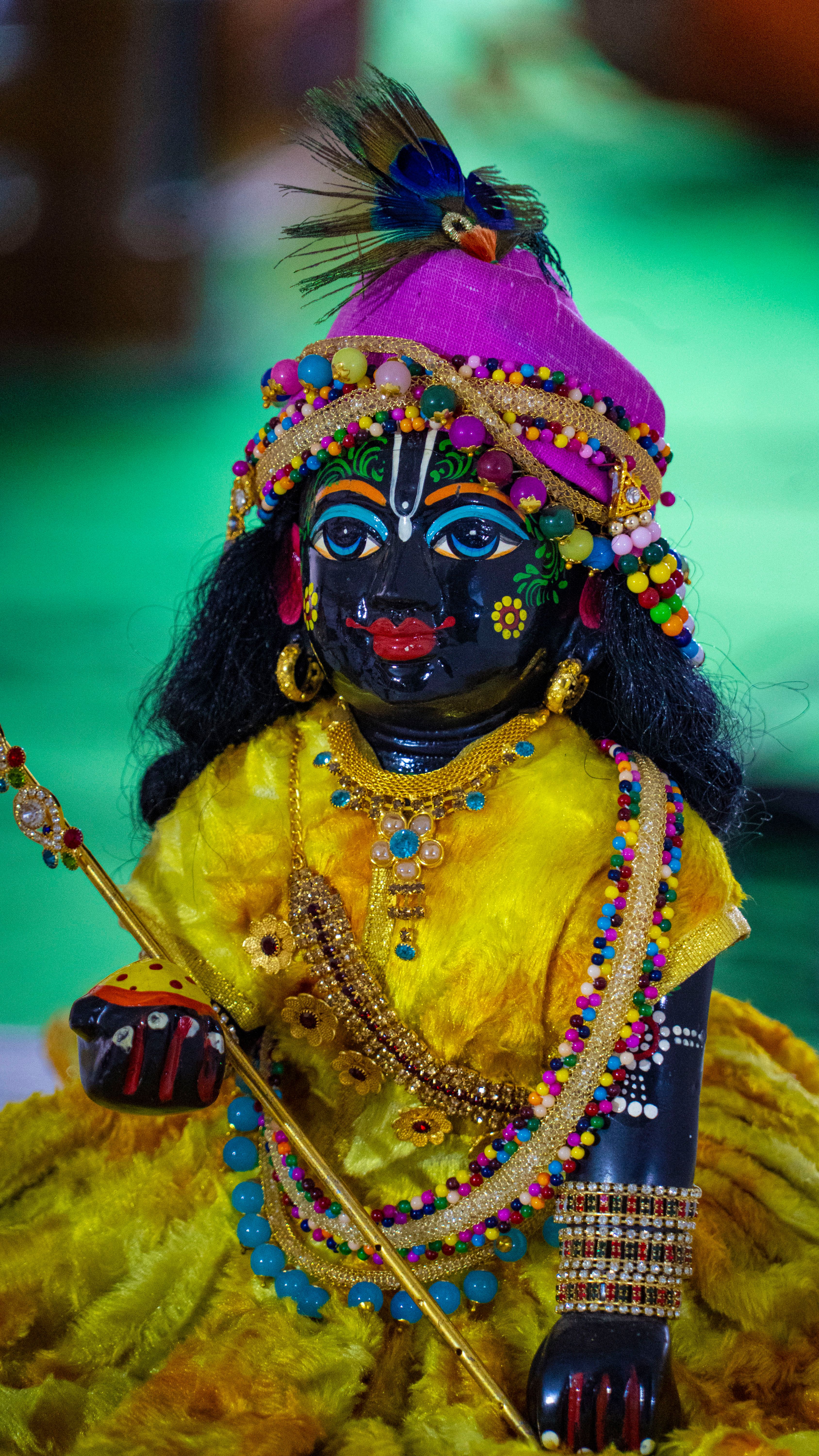 Vibrant traditional Krishna figurine adorned in colorful attire with intricate details.