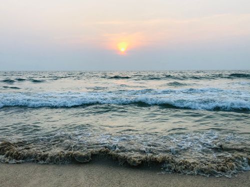 Free A tranquil ocean sunset with gentle waves lapping the sandy shore, providing a peaceful coastal view. Stock Photo