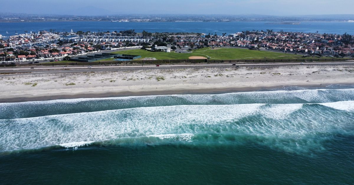 Stunning aerial capture of a coastal city with beachfront and waves.