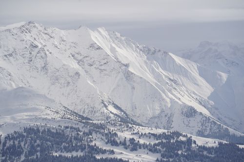 Free Expansive snowy mountain scene with forests, capturing winter's serene beauty. Stock Photo