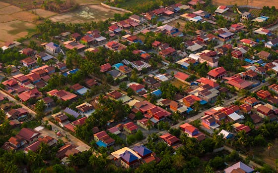 A dynamic aerial view showcasing Krong Chbar Mon's colorful village landscapes in Cambodia, filled with palm trees and residences.