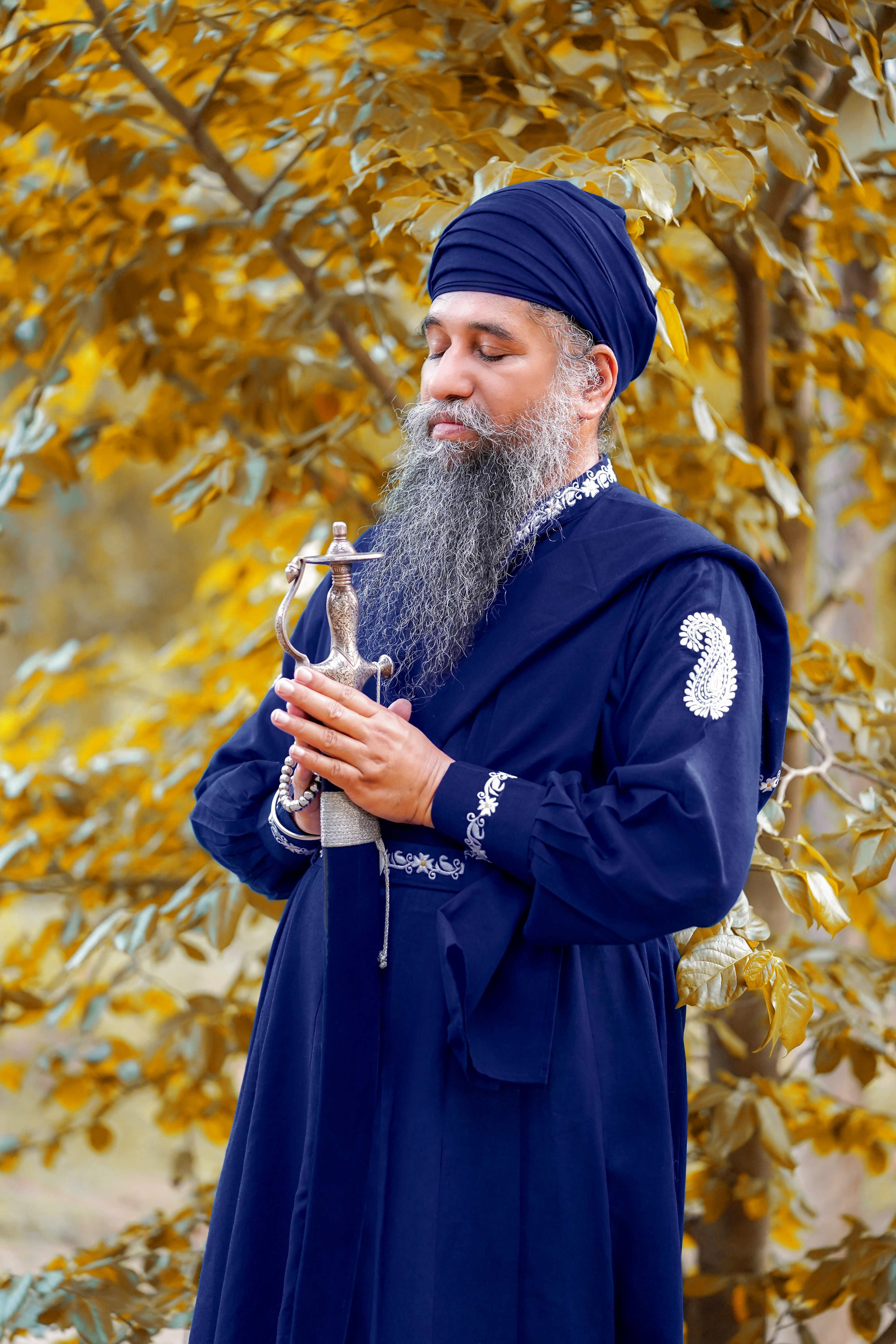 Portrait of a Sikh man in traditional attire, meditating in an outdoor setting.
