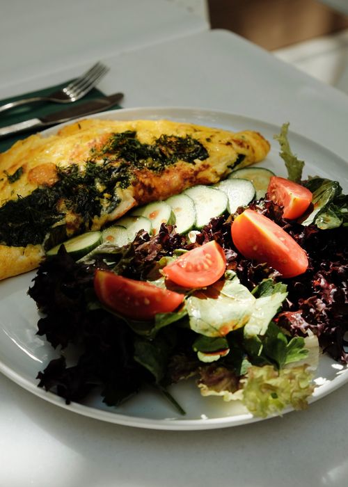 Free Tempting omelet and fresh salad with tomatoes and cucumbers on a white plate. Stock Photo