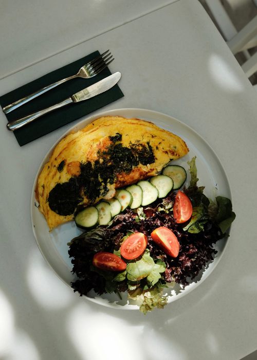 Free Delicious omelet paired with fresh vegetables on a white plate for a healthy breakfast. Stock Photo