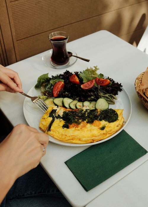 Free Person enjoying a nutritious meal with an omelette and fresh salad on a table. Stock Photo