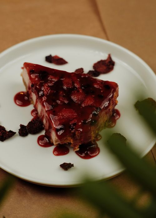 Free A scrumptious slice of cake with strawberry topping and syrup on a white plate, perfect for sweet indulgence. Stock Photo