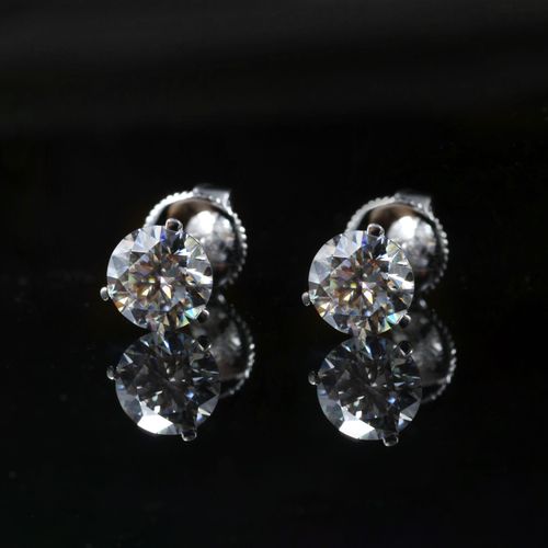Free Close-up of two diamond stud earrings with a reflection on a glossy black surface. Stock Photo