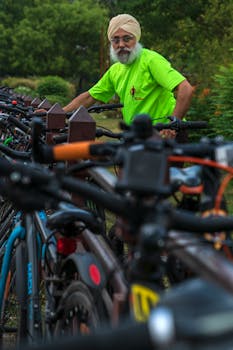 A man in vibrant attire organizes a row of parked bicycles outdoors.