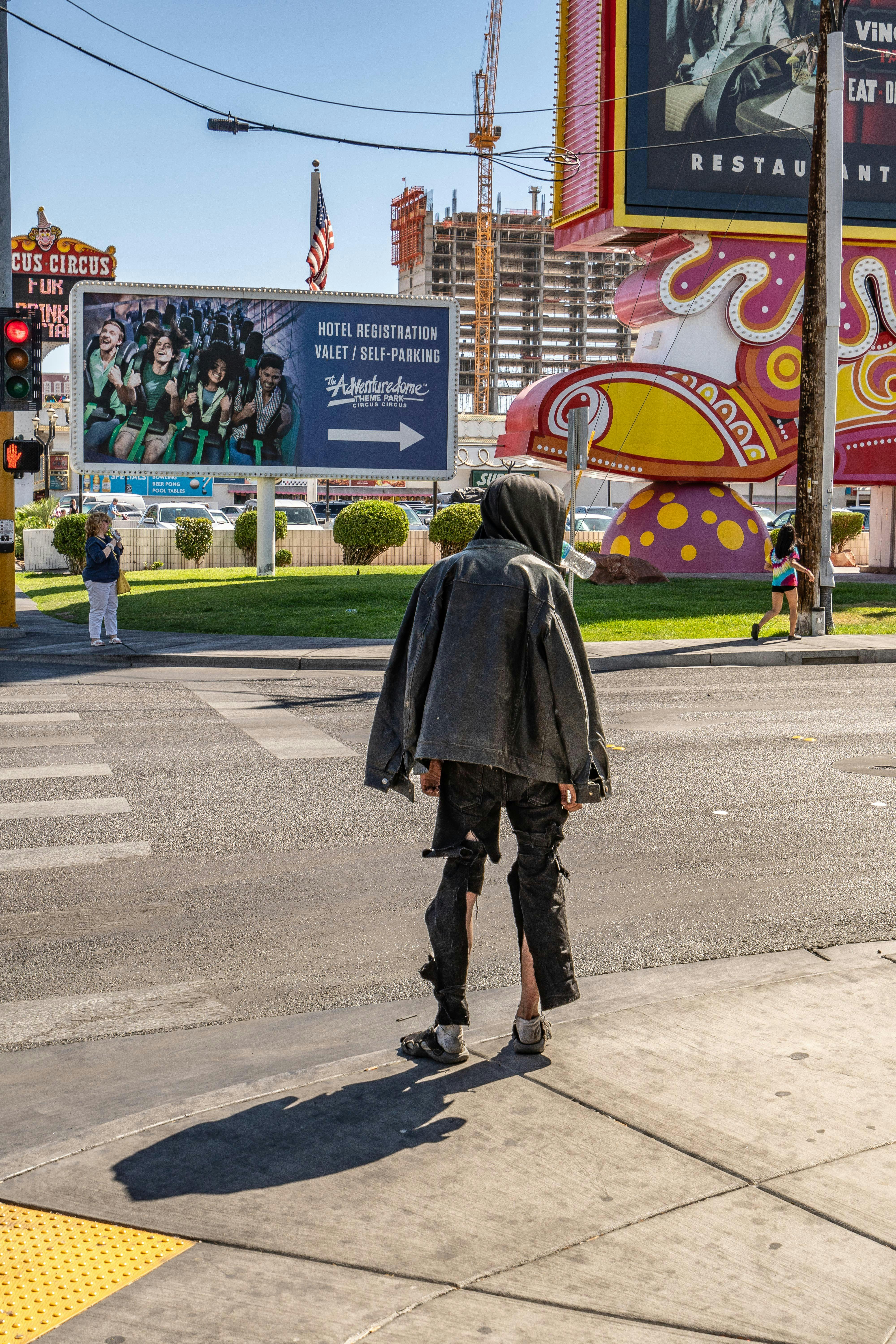 Person in hoodie crossing a vibrant street in Las Vegas past Circus Circus.