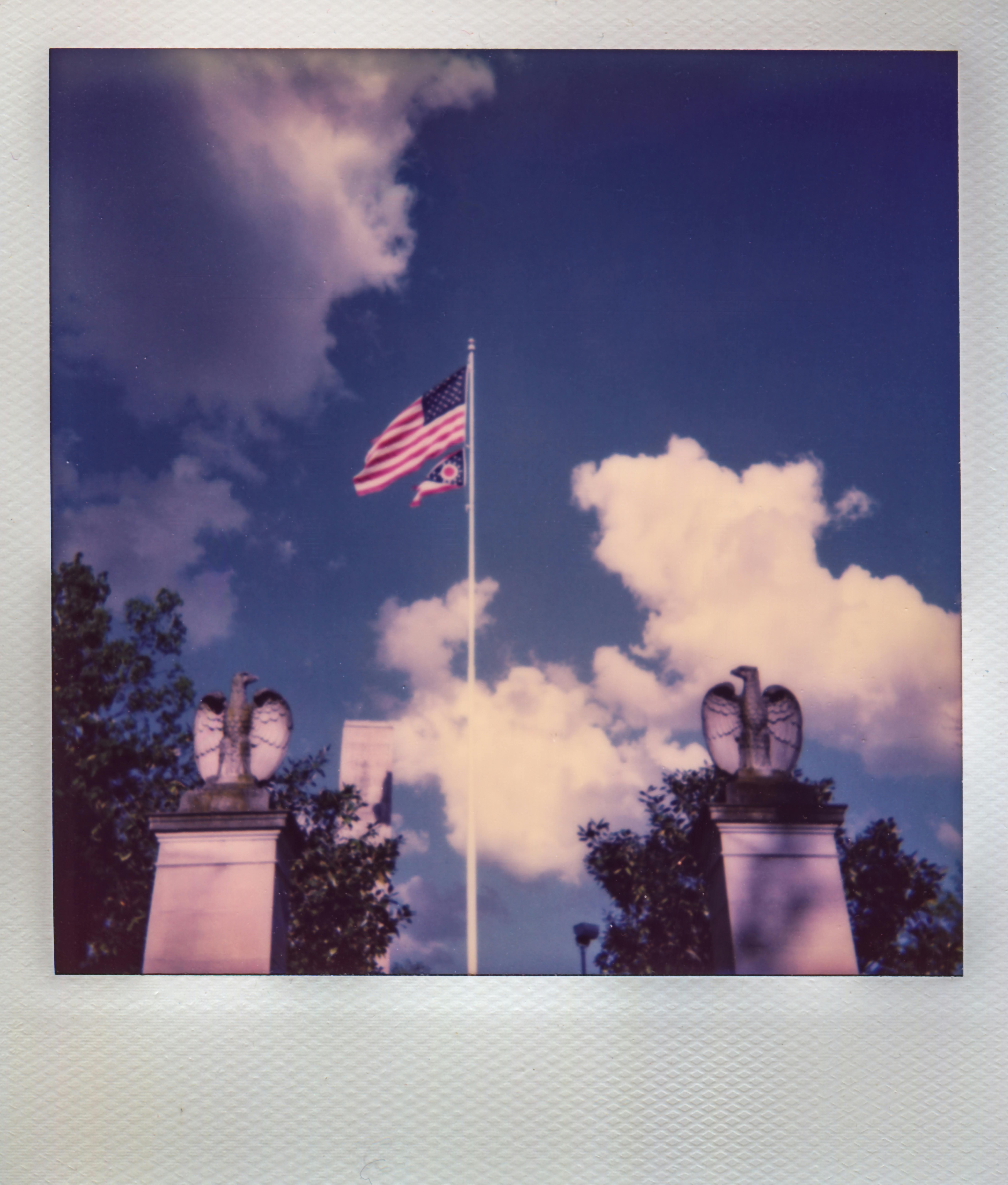 american flag flying on pole between two eagle statues