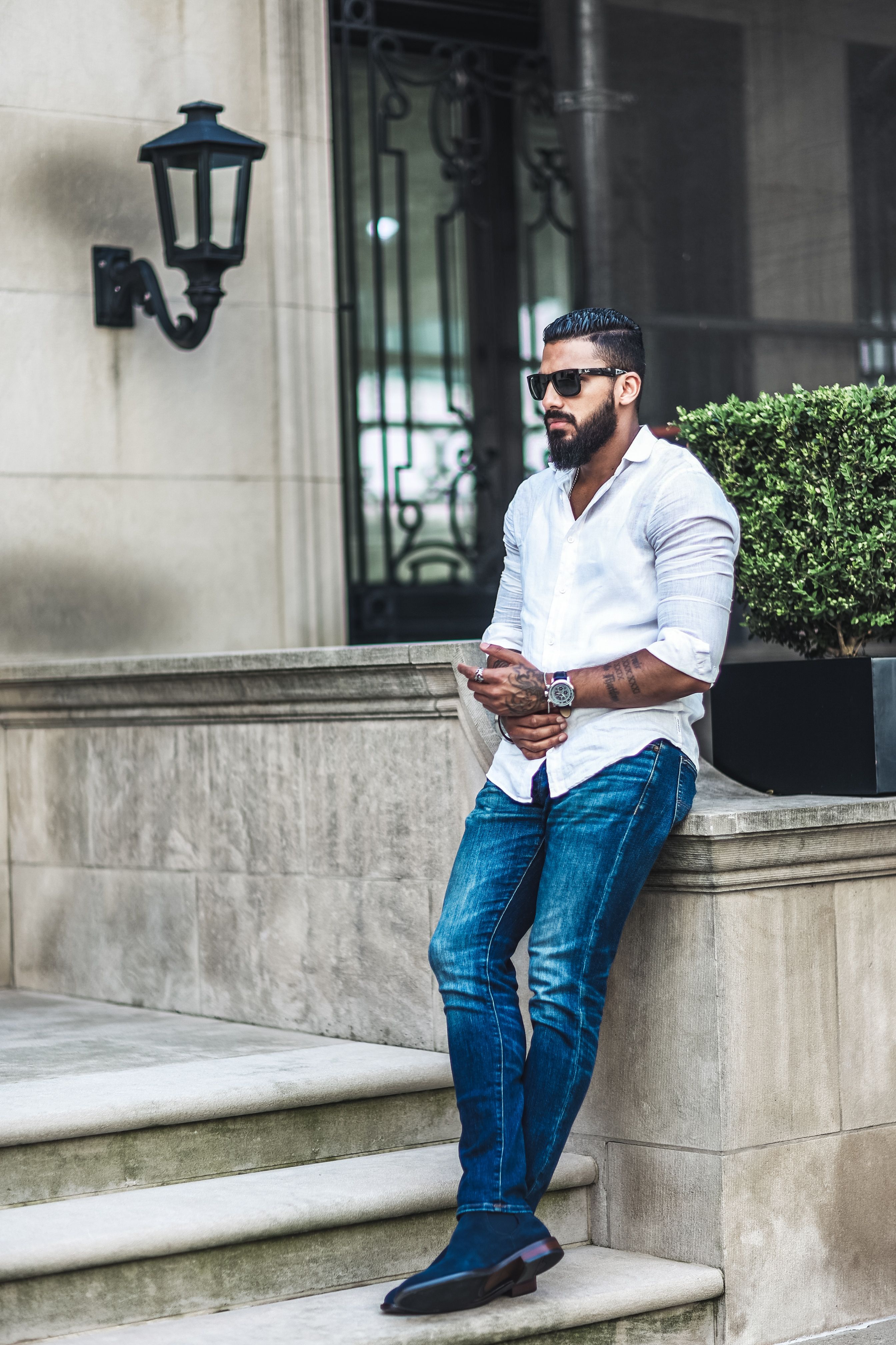A man in a white shirt and jeans is leaning against a wall · Free Stock ...
