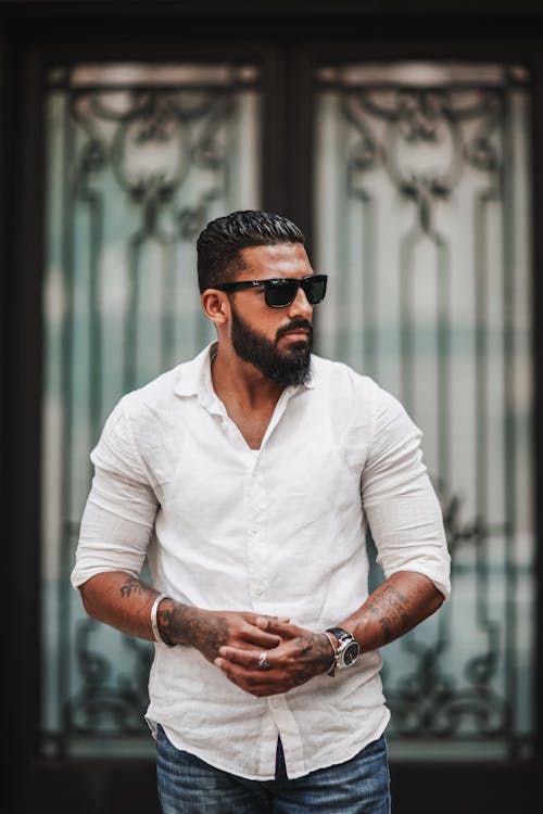 A man with a beard and sunglasses standing in front of a door
