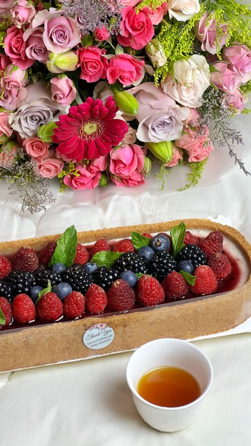 Free Luxurious berry tart with vibrant flower bouquet, perfect for desserts and special occasions. Stock Photo