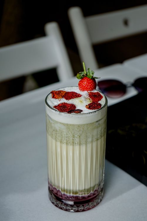 Free Delicious strawberry cream milkshake topped with fresh fruits on a table. Stock Photo