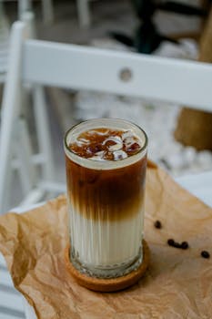 A delicious layered iced coffee with milk on a rustic outdoor table setting.