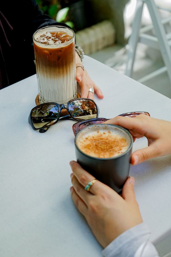 Hands holding iced and hot coffee at a cafe