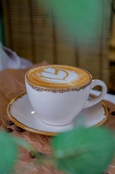 Close-up of a cappuccino with heart-shaped latte art in a decorative cup.
