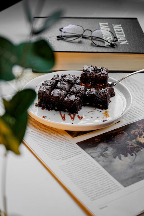 A plate of brownies with glasses and a book