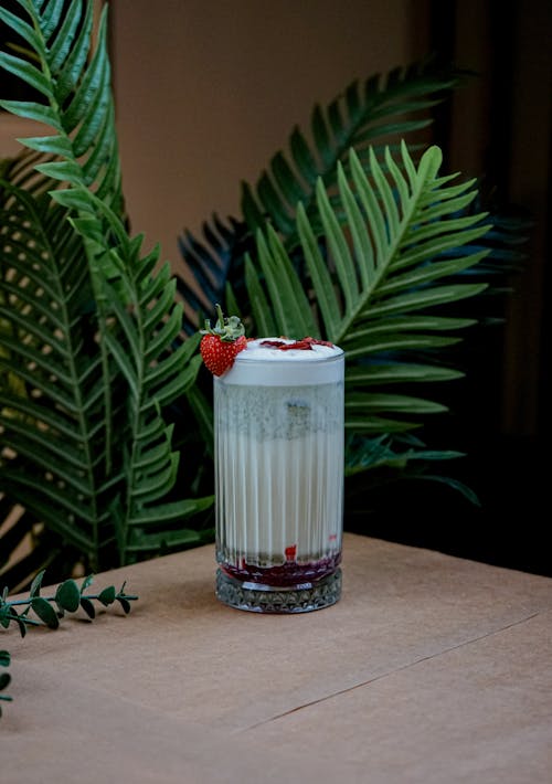 A glass of milk with strawberries and leaves