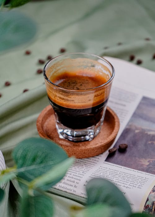 A cup of coffee with a leaf and coffee beans