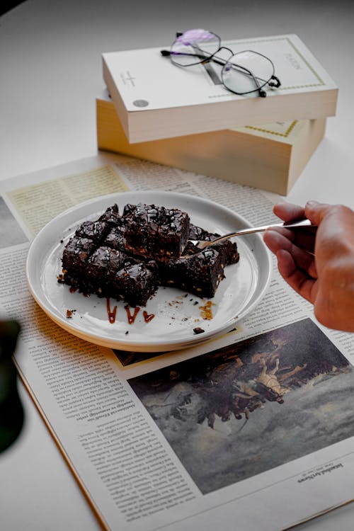 A person is eating a piece of chocolate cake on a plate