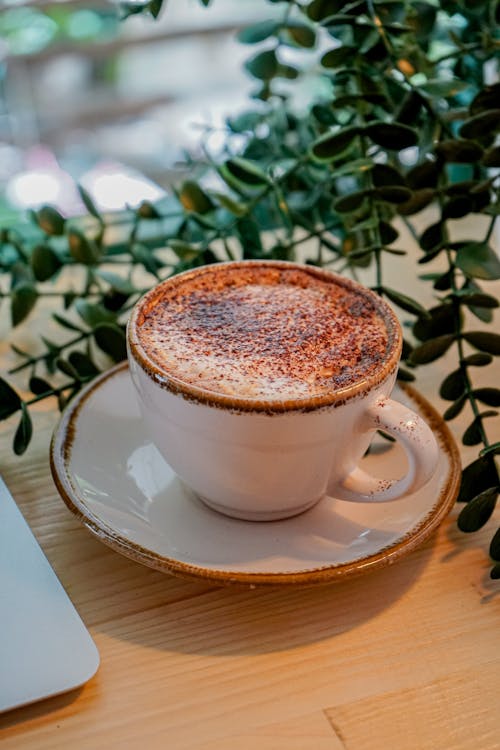 A cup of coffee sits on a table next to a laptop