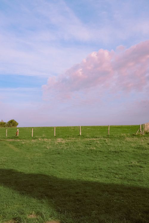 Free Idyllic countryside landscape in France with green pastures and pink clouds. Stock Photo