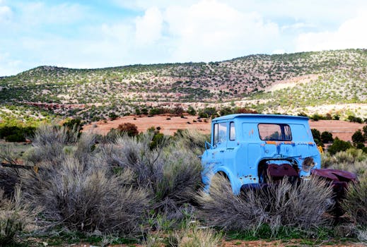 一辆老式的蓝色卡车被遗弃在丘陵崎岖、风景秀丽的沙漠景观中