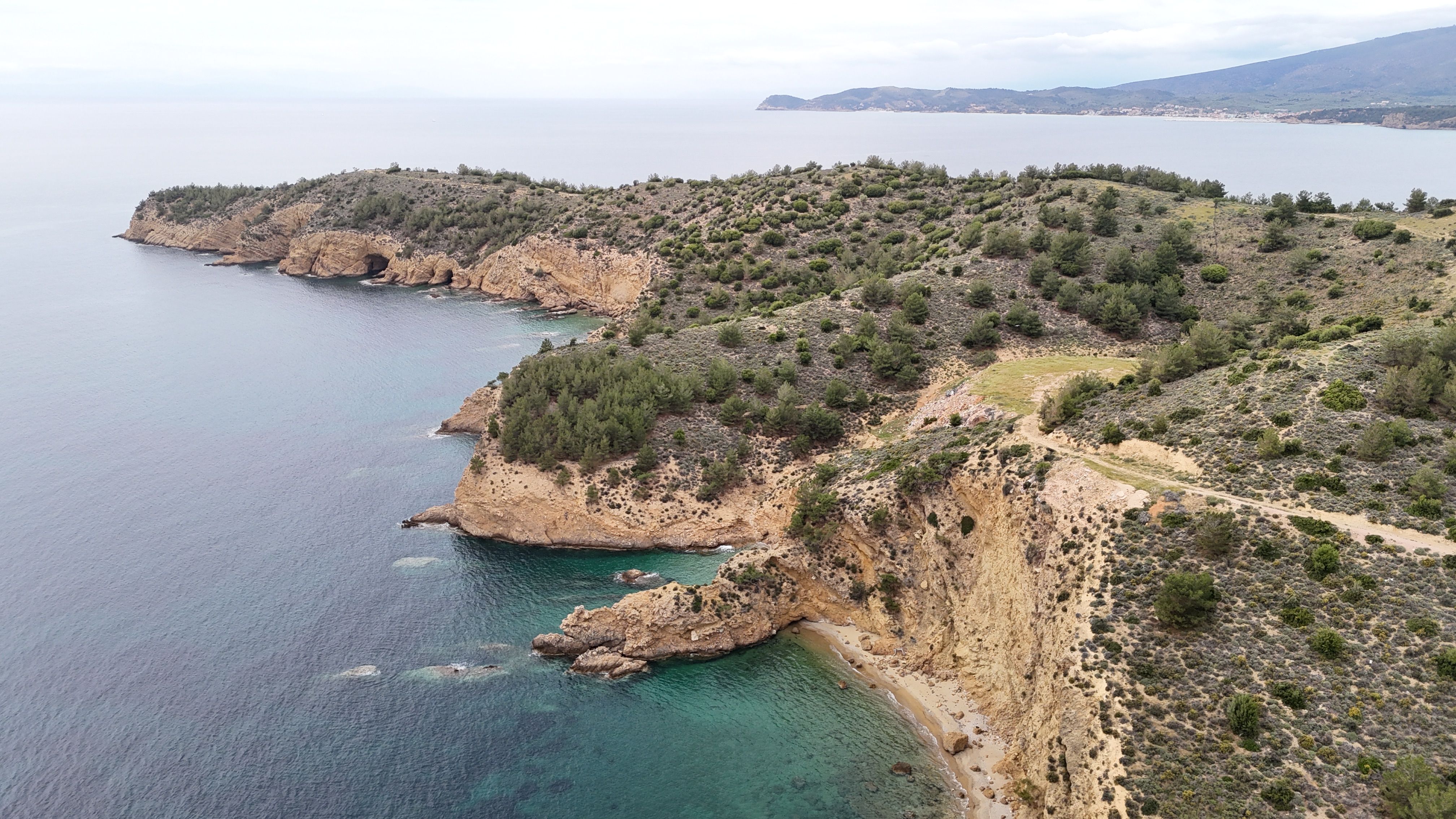 A breathtaking aerial view showcasing coastal cliffs with lush greenery and turquoise waters.