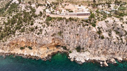 Free Bird's eye view of a coastal rocky cliff with a resort on top during the day. Stock Photo