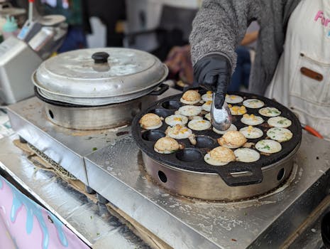 Close-up of a vendor preparing Thai Khanom Krok pancakes at an outdoor market in Leipzig.