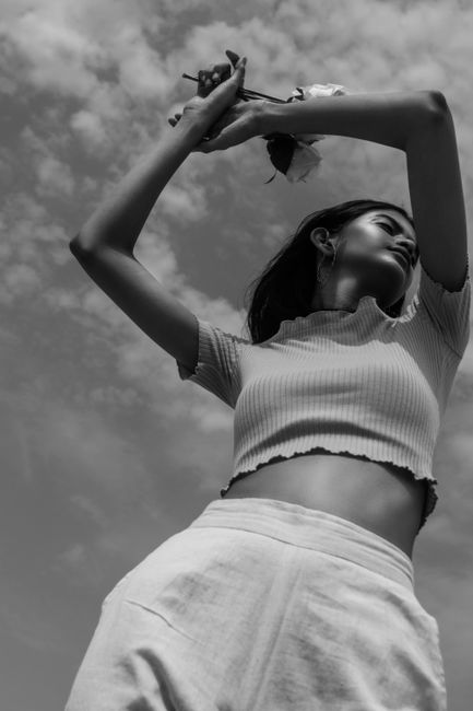 Black and white portrait of a woman posing in a fashion shoot against a cloudy sky in Mumbai.