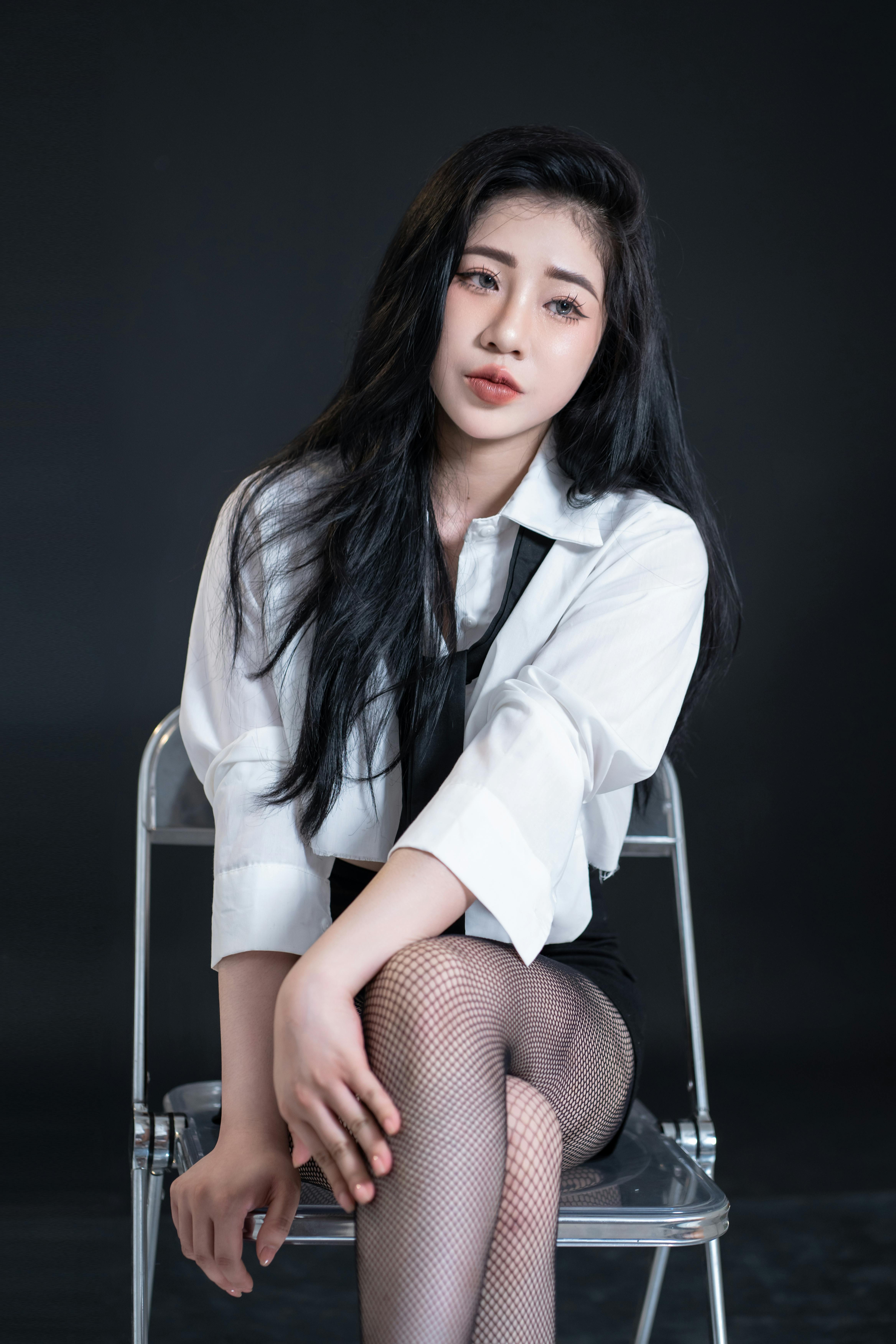Elegant fashion model in a black and white outfit, posing in a studio setting with a dark backdrop.