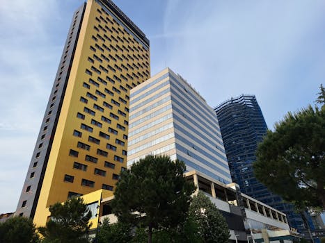 A low-angle shot of towering modern office skyscrapers with a clear blue sky in the background.