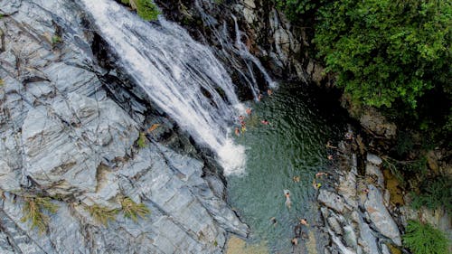 A waterfall is surrounded by trees and people