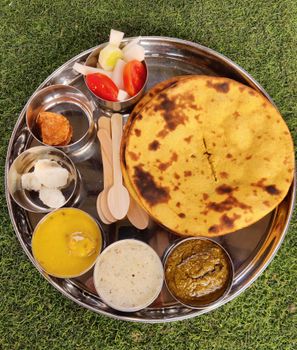A delicious assortment of traditional Indian foods served on a silver plate, showcasing vibrant flavors.