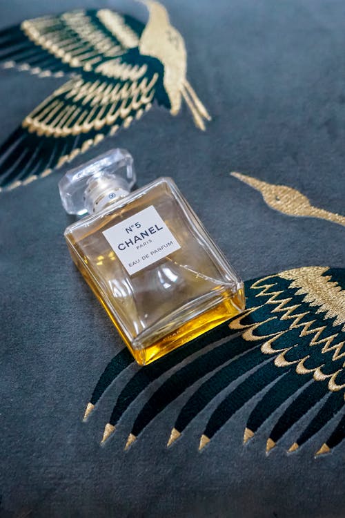 A bottle of perfume sitting on top of a blue and gold patterned fabric