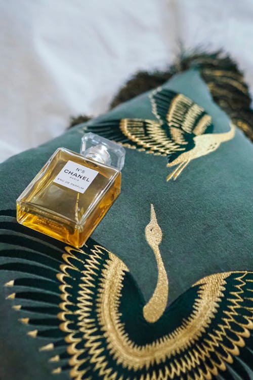 A bottle of perfume sitting on a pillow