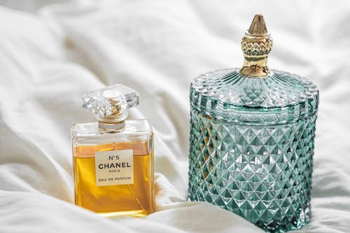 A bottle of perfume and a glass container on a bed
