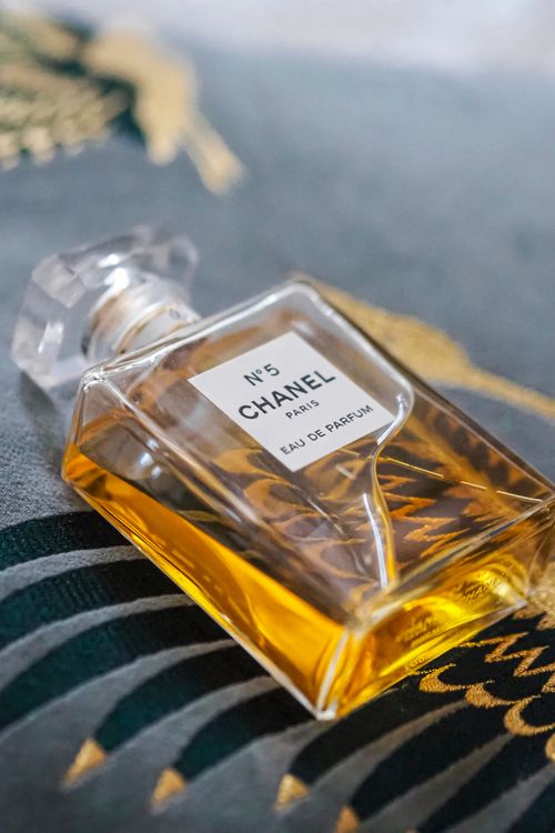 Free Close-up of a tilted Chanel No. 5 perfume bottle displaying luxury elegance. Stock Photo