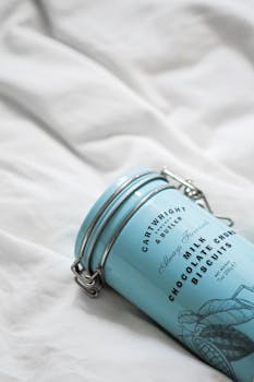 A blue Cartwright and Butler biscuit tin on a white bedspread, emphasizing minimalism.