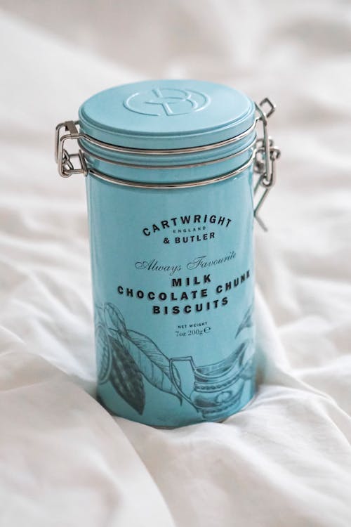 A blue tin with a lid on top of a bed