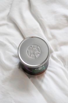 A Starbucks coffee jar with embossed logo on a soft white fabric background, showing elegance and brand identity.