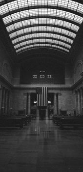 Black and white photo of Union Station's grand hall with an American flag.