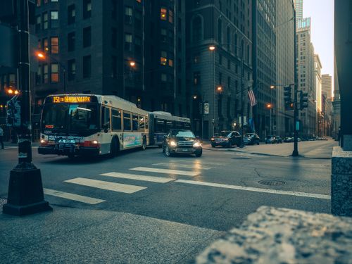 Free City bus and cars navigate a downtown intersection at twilight, urban USA setting. Stock Photo