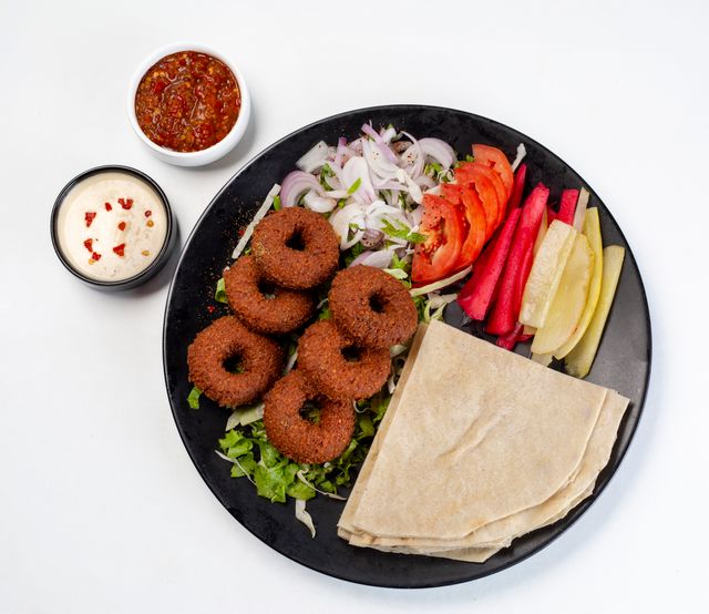 Vibrant falafel platter with fresh vegetables and sauces, ideal for food lovers.