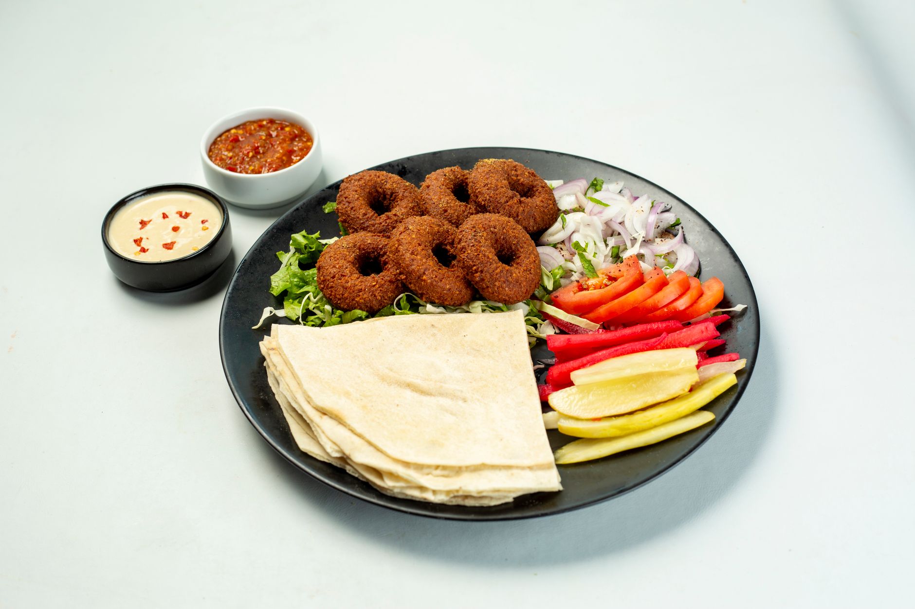 Delicious falafel platter with vibrant vegetables and sauces, perfect for a healthy meal.