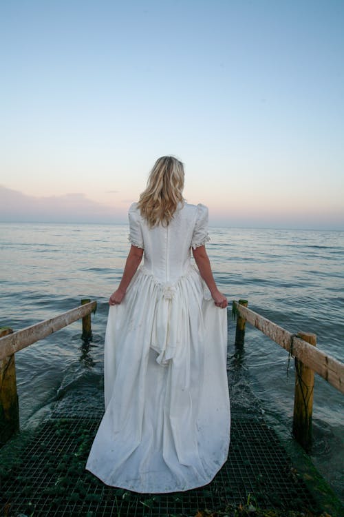 Free Back View Photo of Woman Standing Near Body of Water Stock Photo