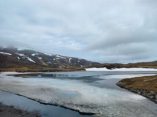 Free Captivating view of a serene lake partially covered with ice amidst a winter landscape. Stock Photo